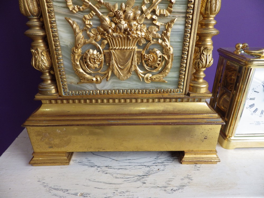 A late 19th-century French gilt bronze mantle clock featuring green onyx panels, fluted side columns, and an ornate floral mount. View II