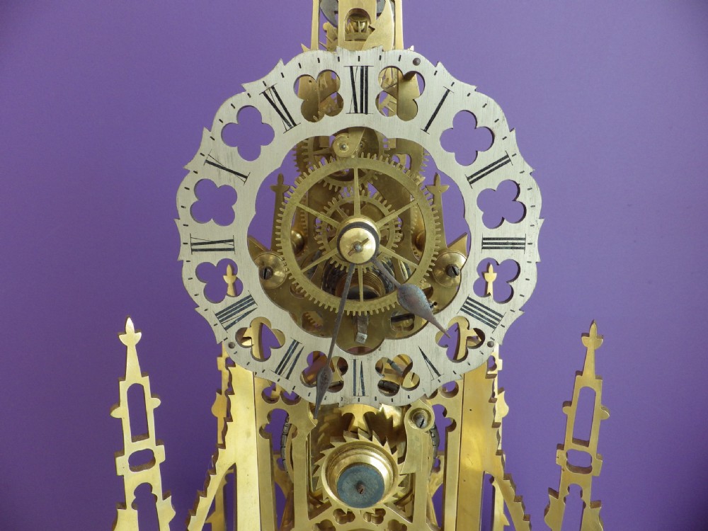 Victorian brass skeleton clock modelled after the Scott Monument featuring an openwork frame, silvered chapter ring, seated figurine, and white marble base. View III