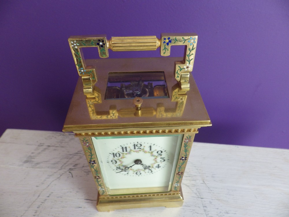 Late nineteenth-century gilt brass French carriage clock featuring polychrome floral enamel borders, a carrying handle, and an enamel dial with Arabic numerals. View IV