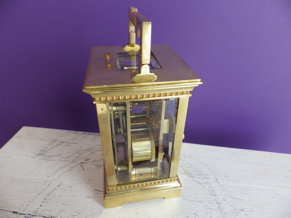 Late nineteenth-century gilt brass French carriage clock featuring polychrome floral enamel borders, a carrying handle, and an enamel dial with Arabic numerals. View V