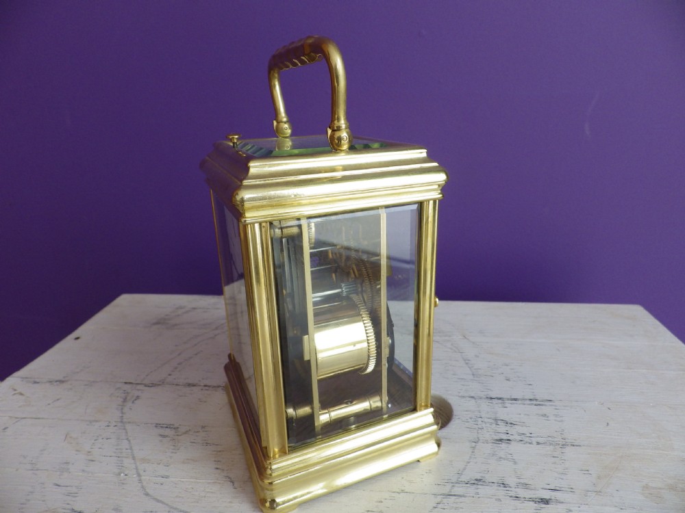 A restored 19th-century French brass gorge case carriage clock featuring a white enamel dial with Roman numerals and a curved carrying handle. View II