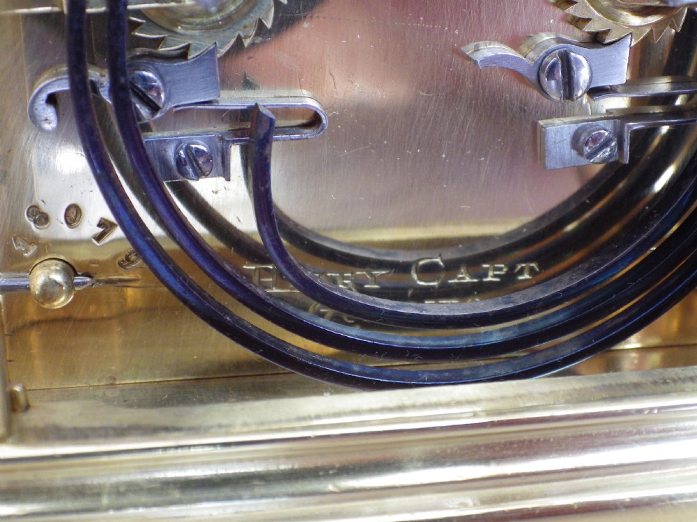 A restored 19th-century French brass gorge case carriage clock featuring a white enamel dial with Roman numerals and a curved carrying handle. View V