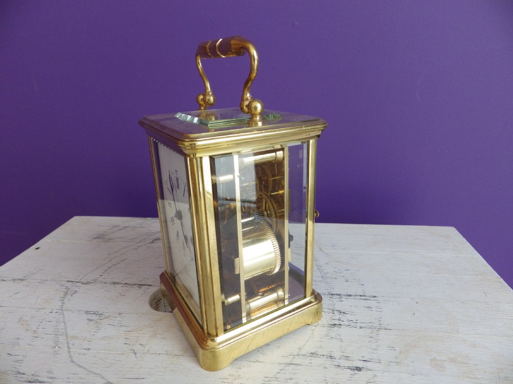 An antique French carriage clock featuring a gilded brass case with clear glass panels, a carrying handle, and a white enamel dial with black Roman numerals. View II