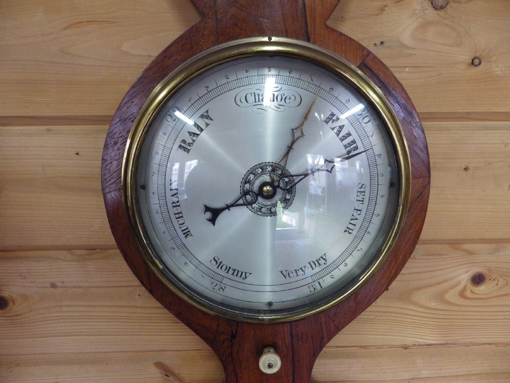 A Victorian wall-mounted mahogany banjo mercury barometer featuring a silvered dial, spirit thermometer, convex mirror, and brass fittings. View III