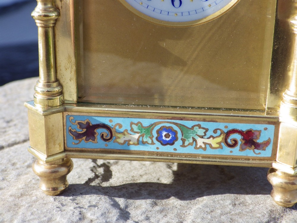 An antique French gilded brass carriage clock featuring polychrome enamel bandings, turned corner columns, and a white circular dial with Arabic numerals. View V