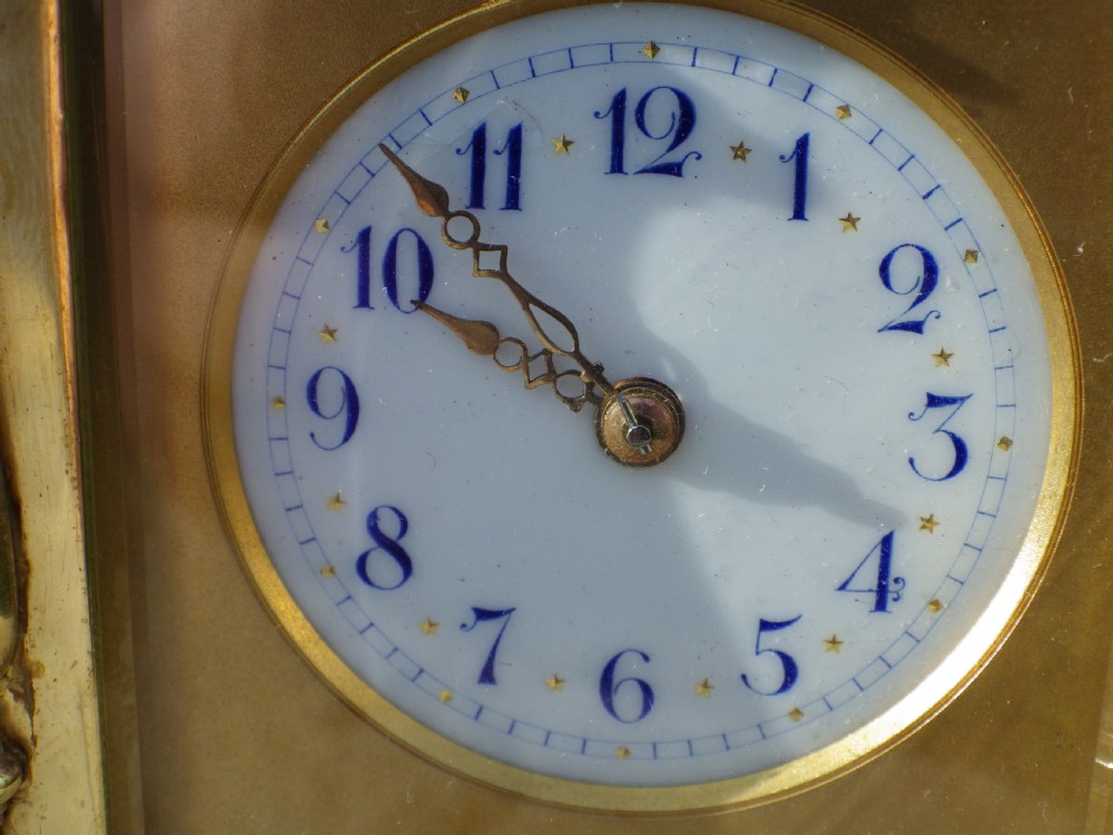 An antique French gilded brass carriage clock featuring polychrome enamel bandings, turned corner columns, and a white circular dial with Arabic numerals. View VII
