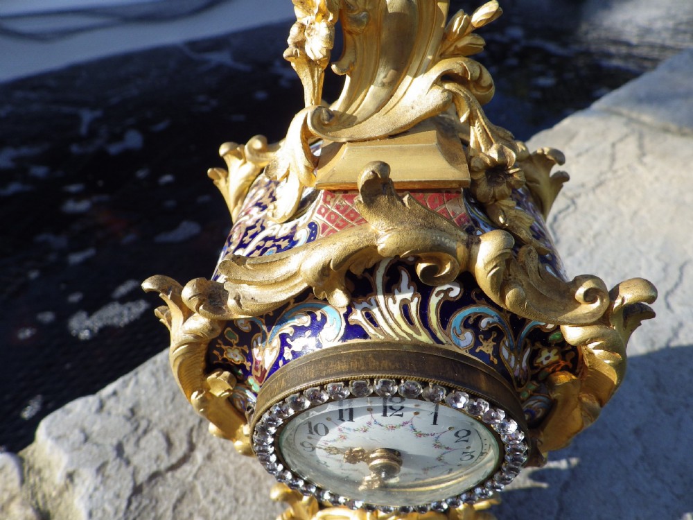 A late 19th-century French Rococo style gilded bronze miniature clock adorned with blue enamel detail and a jewelled crystal bezel surrounding a white dial. View III
