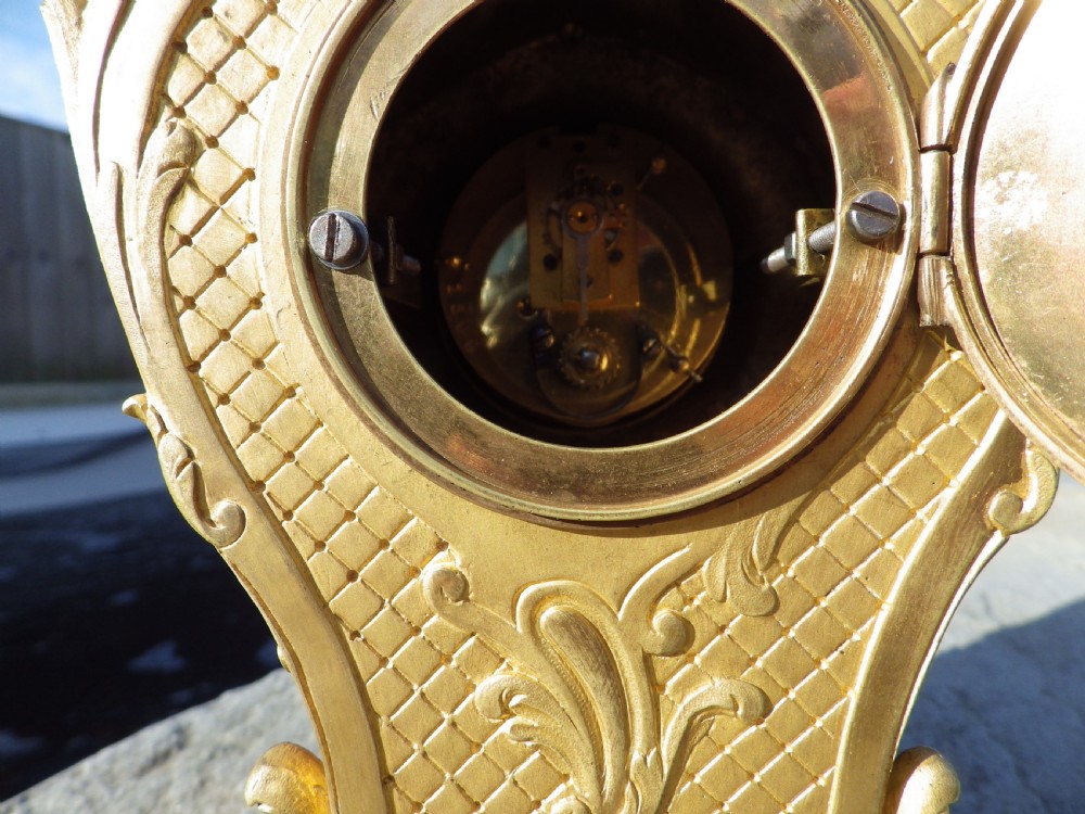 A late 19th-century French Rococo style gilded bronze miniature clock adorned with blue enamel detail and a jewelled crystal bezel surrounding a white dial. View VII