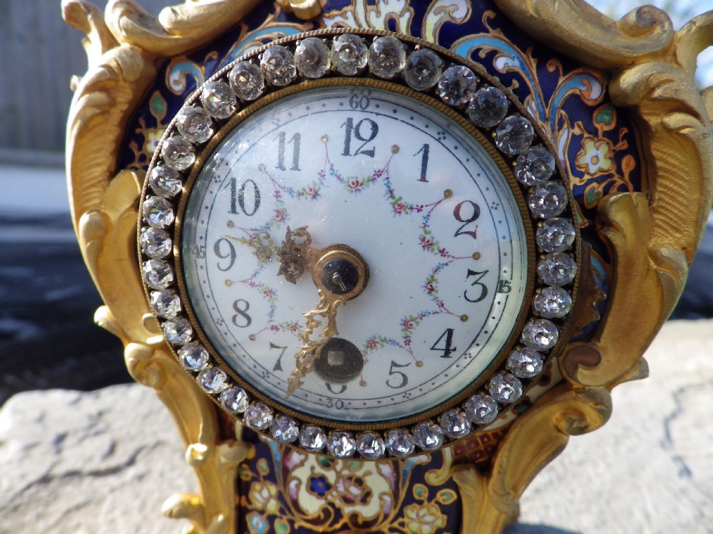 A late 19th-century French Rococo style gilded bronze miniature clock adorned with blue enamel detail and a jewelled crystal bezel surrounding a white dial. View VIII