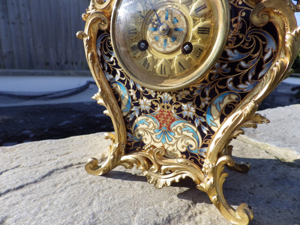 A late 19th-century French Rococo revival mantel clock crafted in gilt bronze ormolu with blue and cream champleve enamel detailing. View II