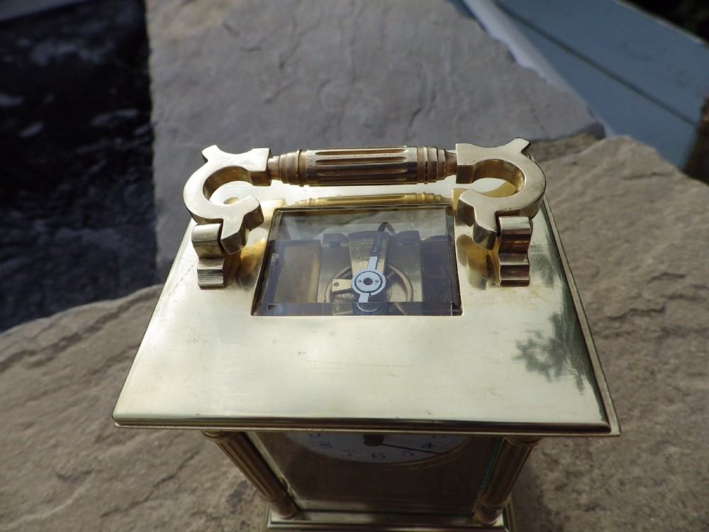 A late nineteenth-century French brass carriage clock featuring fluted corner columns, bevelled glass, an engine-turned brass mask, and a white enamel dial. View V