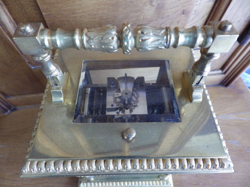 A nineteenth-century French gilt brass carriage clock featuring a top carrying handle, decorative corner columns, and hand-painted enamel panels depicting figures. View VI
