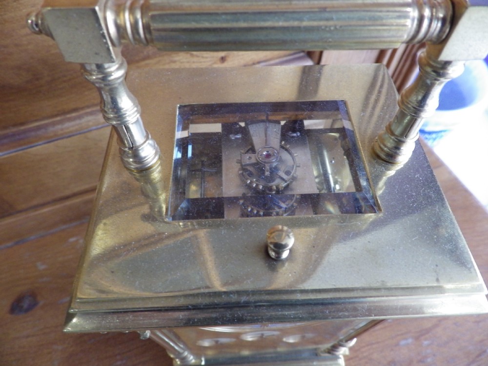 A French gilt brass carriage clock featuring fluted Corinthian columns, a white enamel dial with a painted moon phase aperture, and three subsidiary calendar dials. View VI