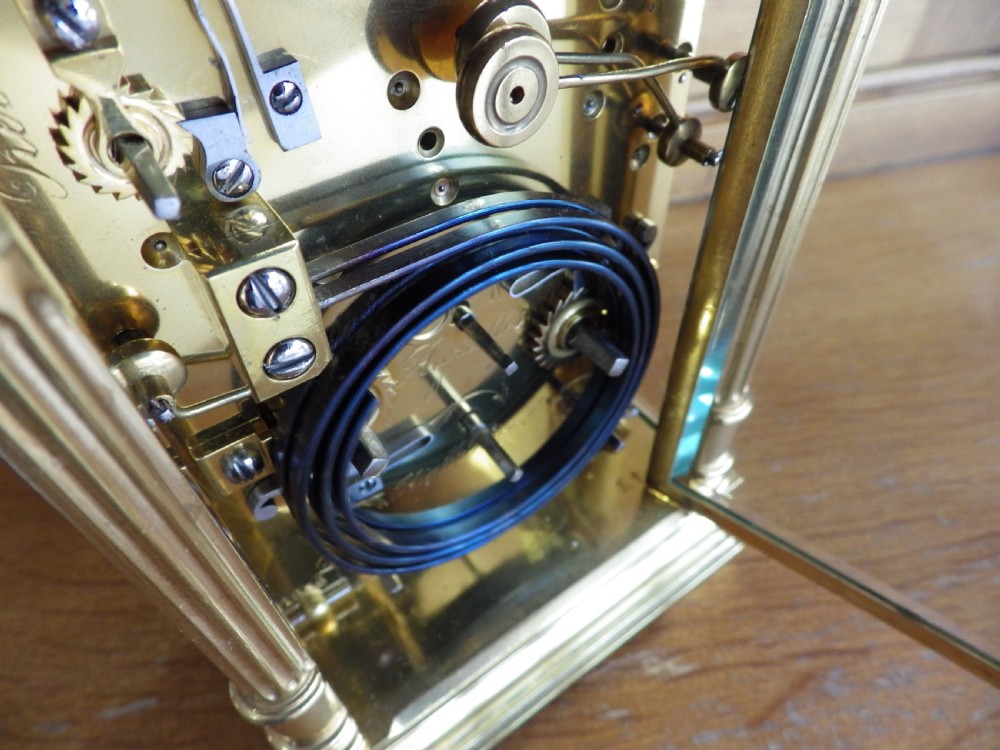 A French gilt brass carriage clock featuring fluted Corinthian columns, a white enamel dial with a painted moon phase aperture, and three subsidiary calendar dials. View VIII