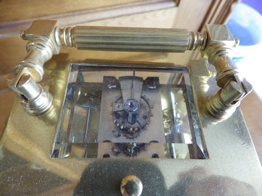 A French gilt brass carriage clock featuring fluted Corinthian columns, a white enamel dial with a painted moon phase aperture, and three subsidiary calendar dials. View IX