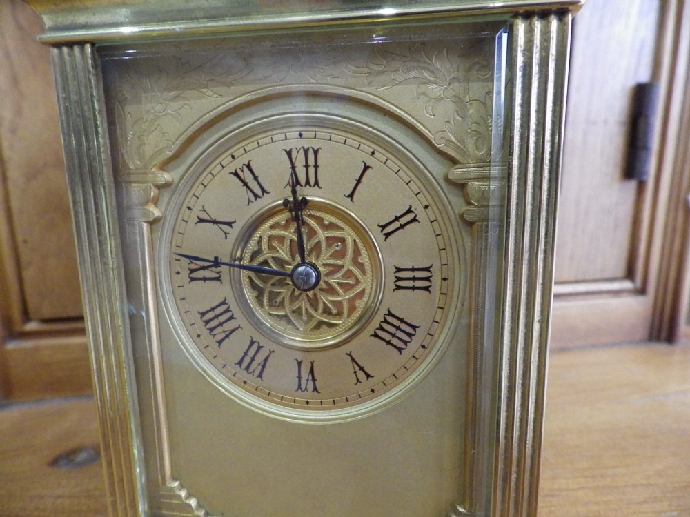 A late nineteenth-century French gilt brass repeating carriage clock featuring glass panels, a carrying handle, and a dial with Roman numerals. View III