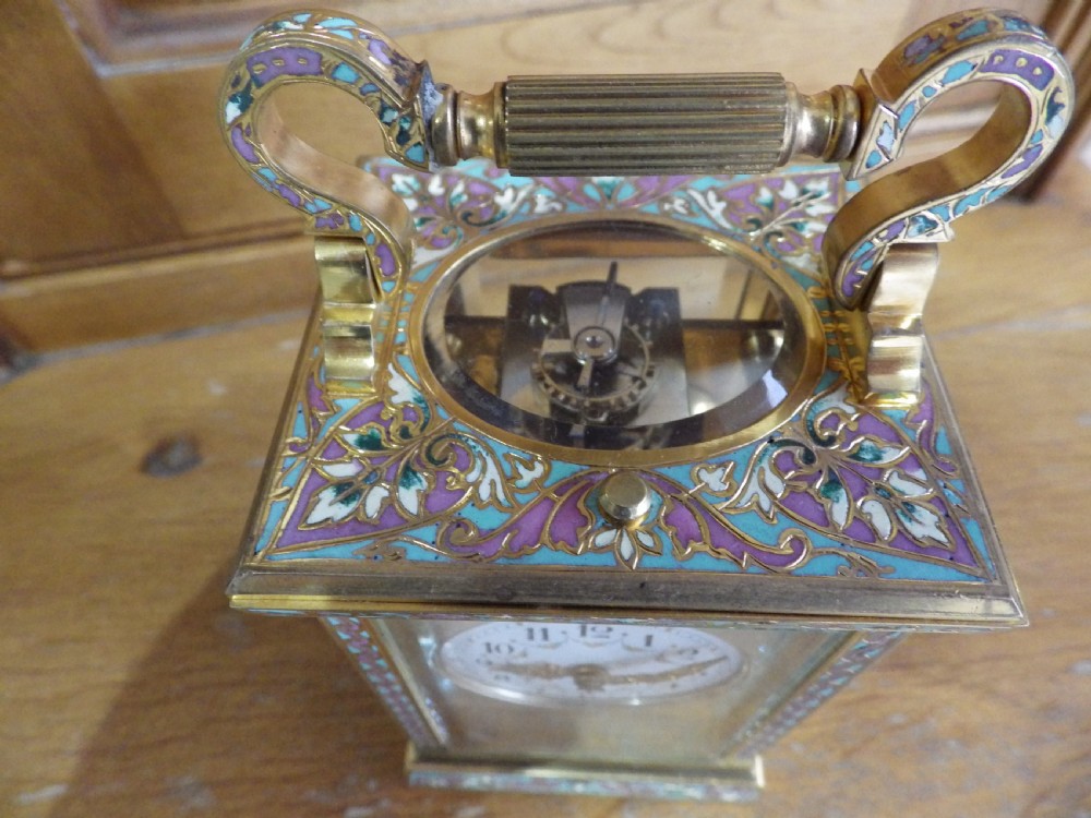 A late 19th-century French brass carriage clock featuring turquoise and purple champleve enamel borders, clear glass panels, and a painted white enamel dial. View IV