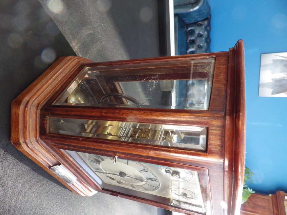An Edwardian mahogany mantel clock featuring glazed side panels, a silvered metal dial with Roman numerals, and a silver presentation plaque mounted at the base. View II
