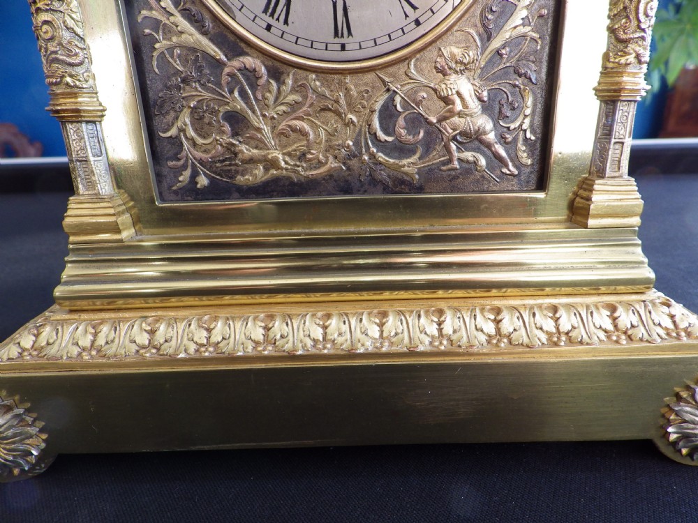 An 1870s French solid brass mantel clock featuring ornate filigree, corner columns, a finial cresting, and a Roman numeral dial. View II