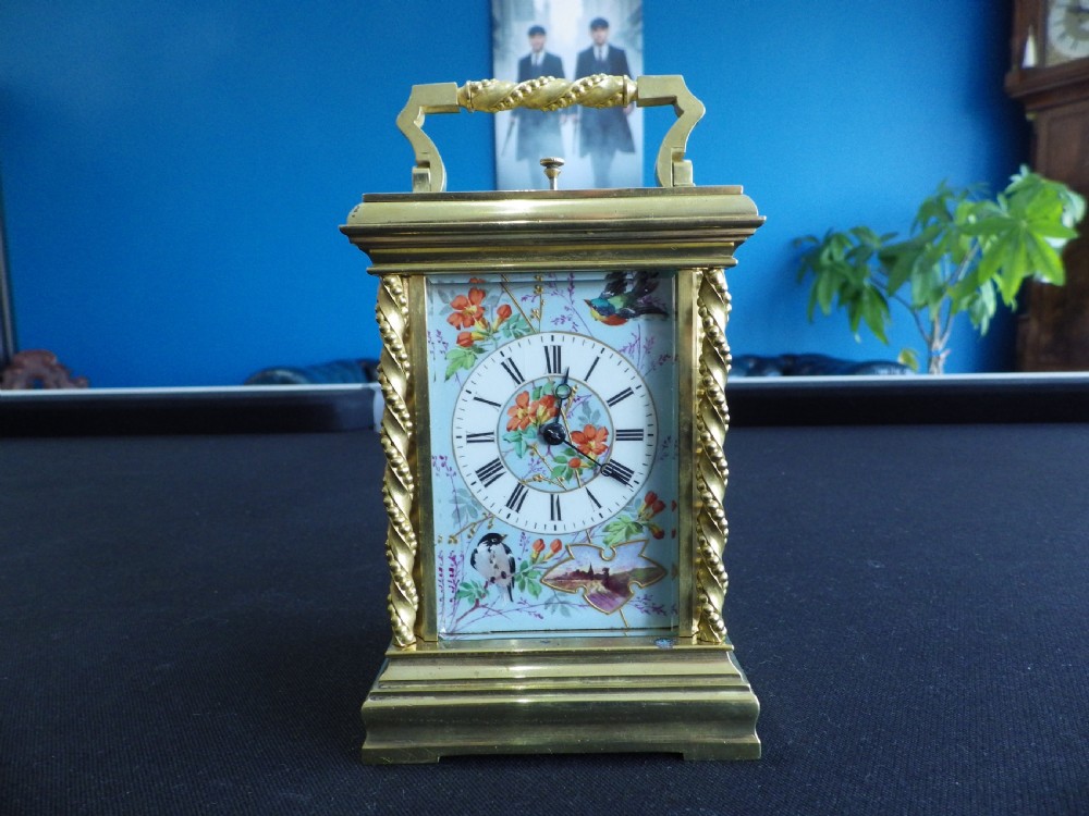 A late 19th-century French gilt brass repeating carriage clock featuring rope-twist columns and a light blue enamel dial panel decorated with painted birds and floral motifs.