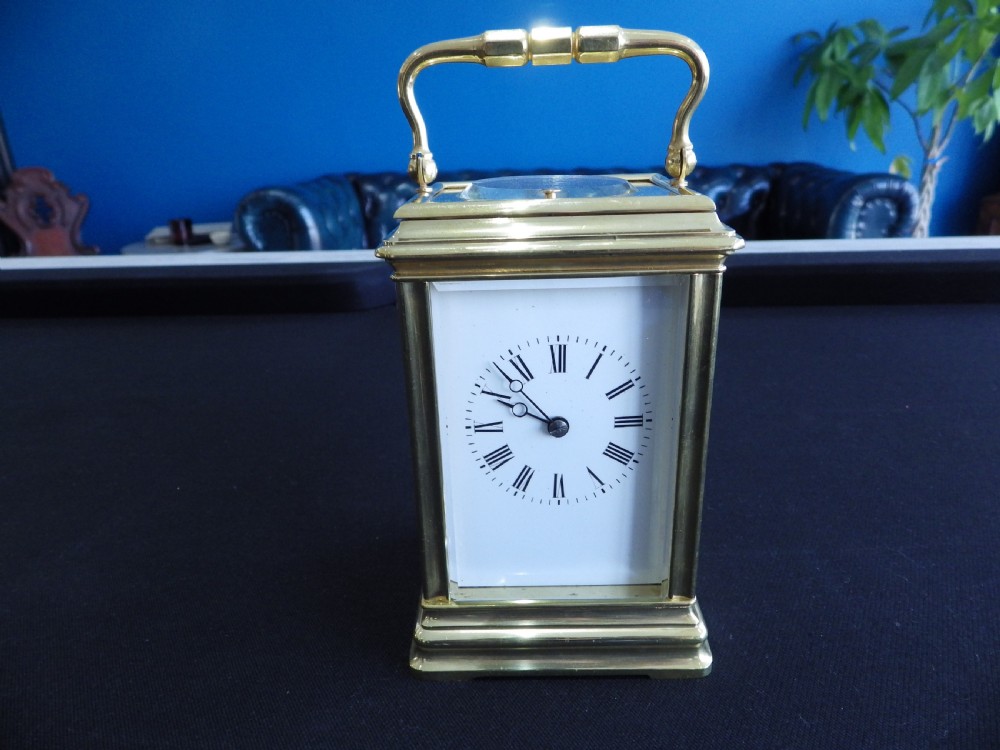 A restored 19th-century French repeater carriage clock featuring a polished brass case with clear glass panels, a top handle, and a white enamel dial with black Roman numerals.