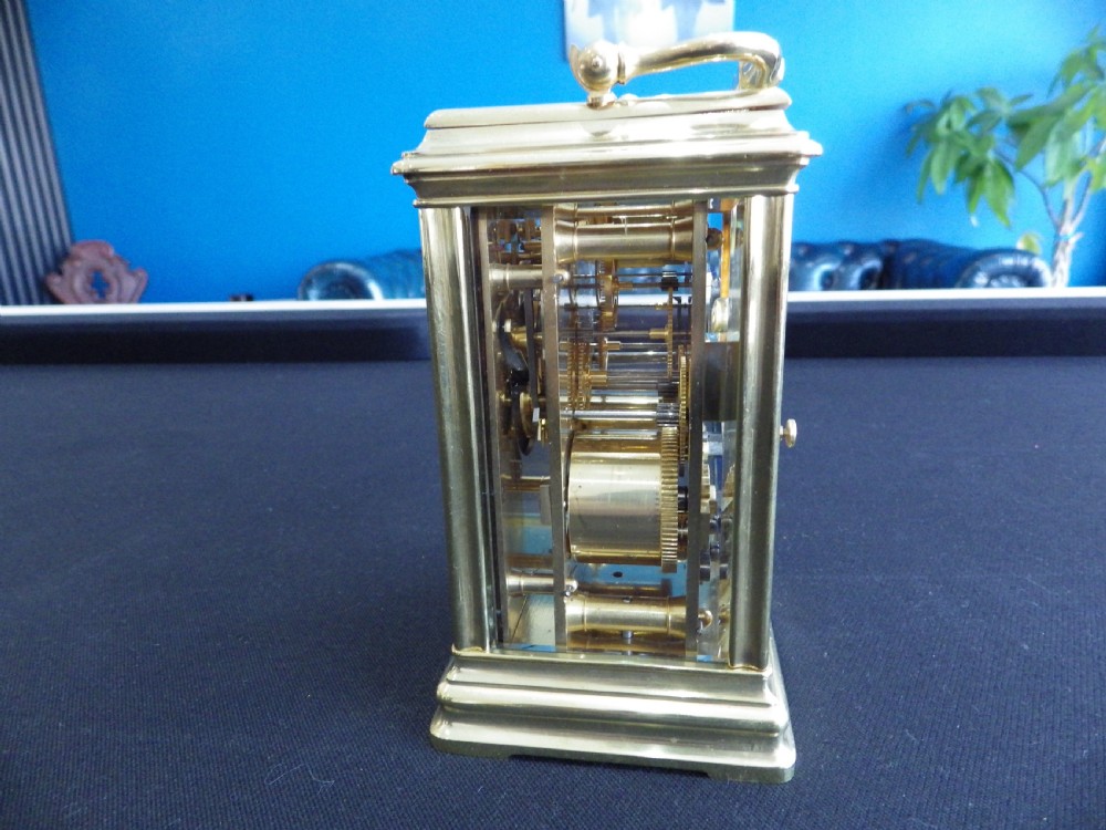 A restored 19th-century French repeater carriage clock featuring a polished brass case with clear glass panels, a top handle, and a white enamel dial with black Roman numerals. View II