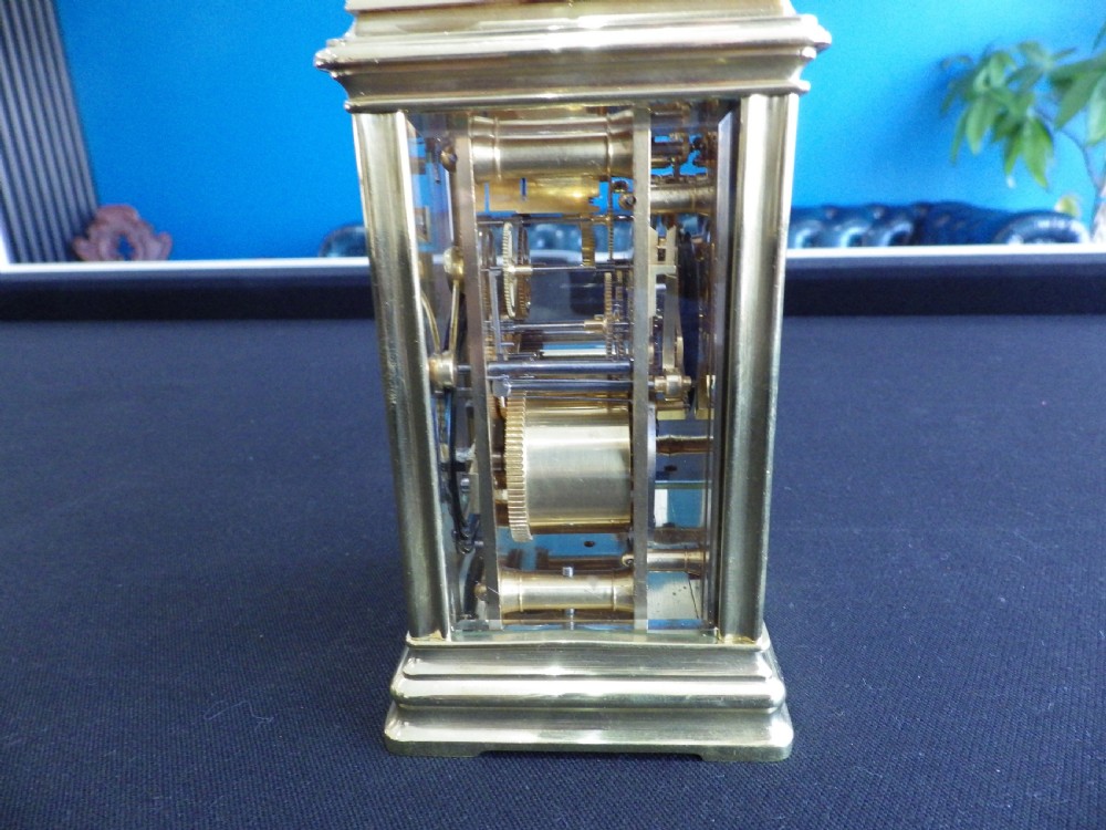 A restored 19th-century French repeater carriage clock featuring a polished brass case with clear glass panels, a top handle, and a white enamel dial with black Roman numerals. View IV