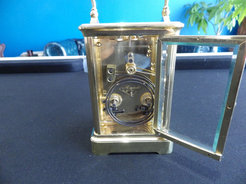 A late 19th-century French brass carriage clock featuring glass side panels, a top carrying handle, and a white enamel dial with black Roman numerals. View III
