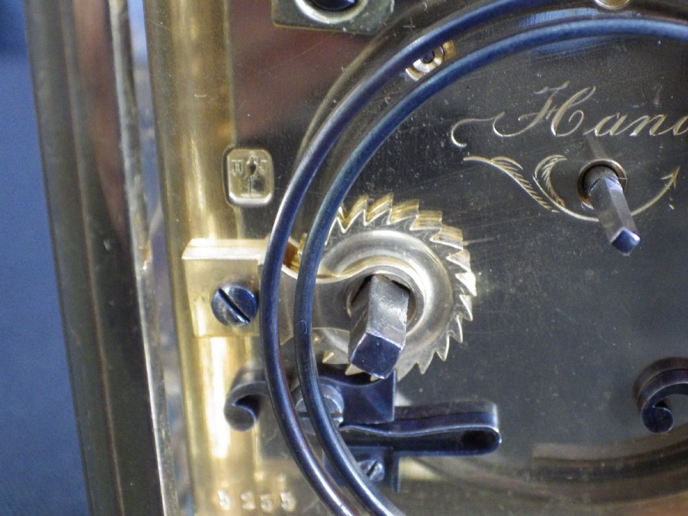 A late 19th-century French brass carriage clock featuring glass side panels, a top carrying handle, and a white enamel dial with black Roman numerals. View IV