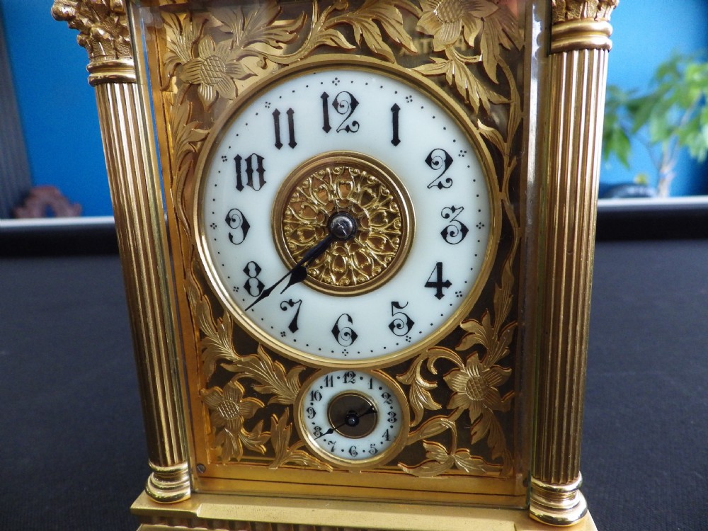 A late nineteenth-century French gilt brass carriage clock featuring fluted corner columns, relief floral masking, and a white enamel dial with black Arabic numerals. View II
