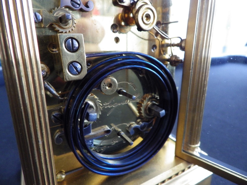 A late nineteenth-century French gilt brass carriage clock featuring fluted corner columns, relief floral masking, and a white enamel dial with black Arabic numerals. View V