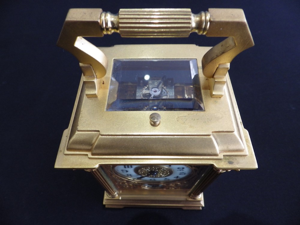 A late nineteenth-century French gilt brass carriage clock featuring fluted corner columns, relief floral masking, and a white enamel dial with black Arabic numerals. View VII