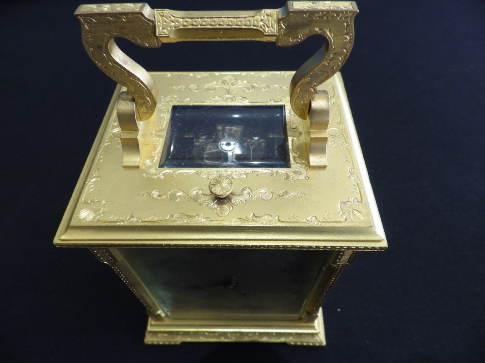 A nineteenth-century French brass carriage clock featuring an engraved rectangular case, a silvered dial with Arabic numerals, and a decorative top handle. View II
