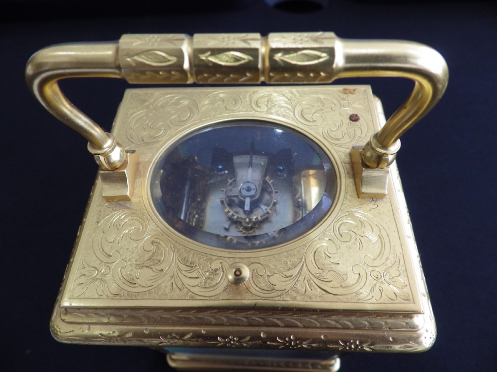 An engraved gilded brass carriage clock featuring a white enamel dial with Roman numerals, a sub-dial, Chinese inscriptions, and a hinged top handle. View III