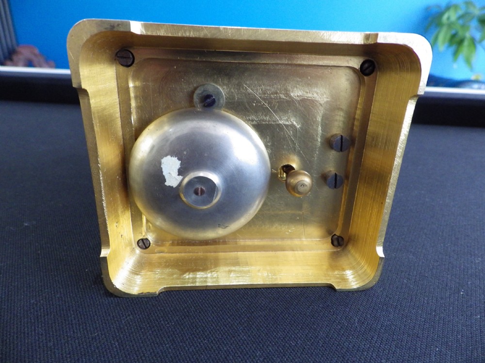 An engraved gilded brass carriage clock featuring a white enamel dial with Roman numerals, a sub-dial, Chinese inscriptions, and a hinged top handle. View VII