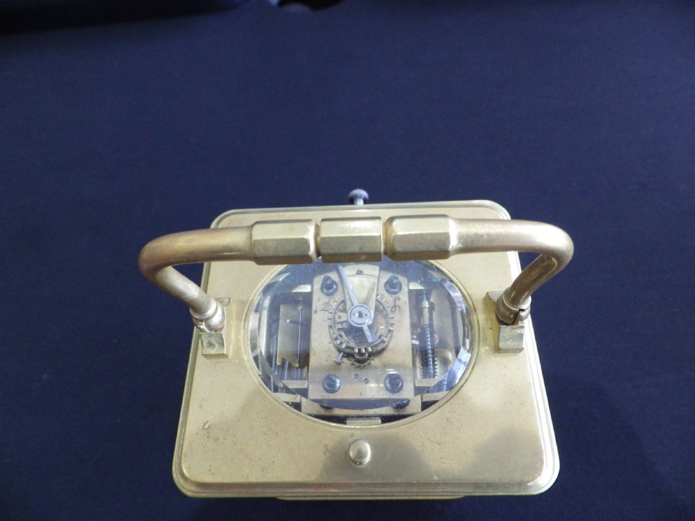 A late 19th-century French brass carriage clock featuring rectangular glass side panels, a top carrying handle, a white enamel dial with Roman numerals, and a repeater push-button. View II