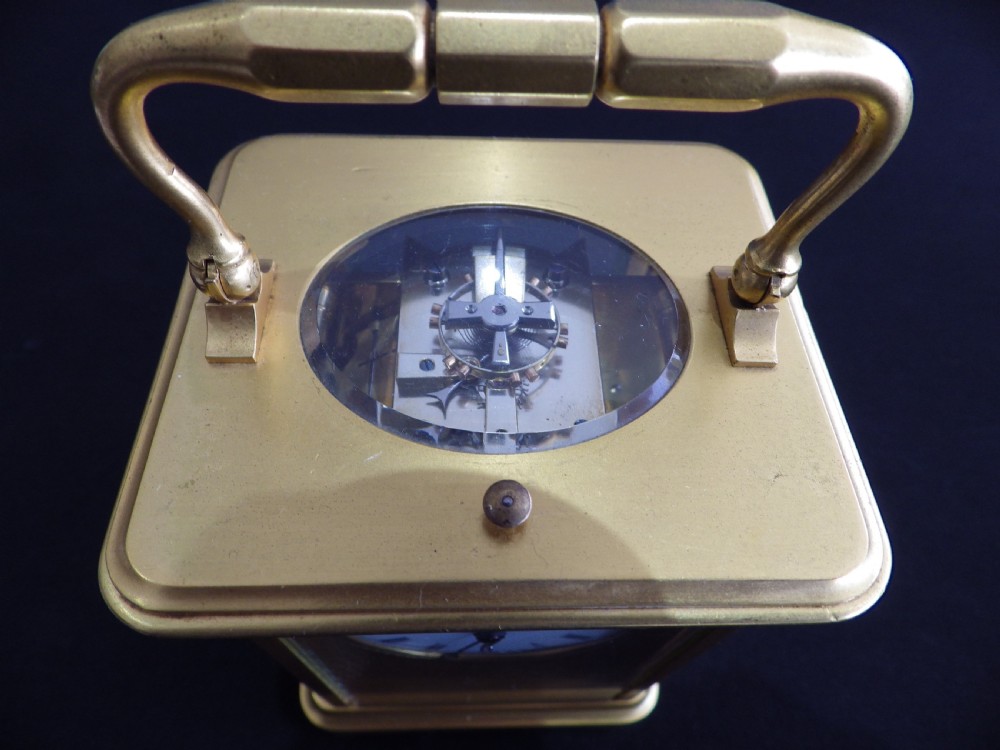A nineteenth-century French gilded brass carriage clock with a top handle, side glass panels, and a white enamel Roman numeral dial set into a textured gilt surround. View V