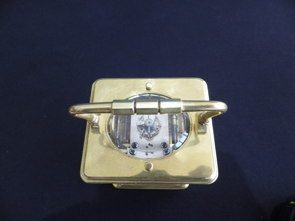 A rectangular antique brass French carriage clock featuring bevelled glass side panels, a top carrying handle, and a white enamelled dial with black Roman numerals. View II