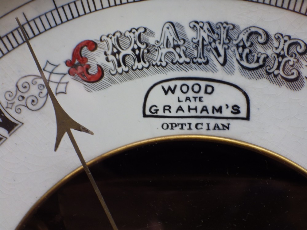 A diamond-shaped carved mahogany wall barometer featuring an open centre circular dial with black and red text. View III