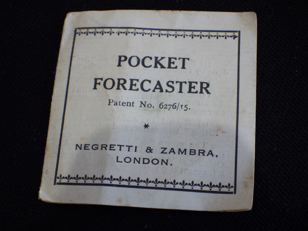 An antique circular Negretti and Zambra pocket weather forecaster made from cream and yellow celluloid with printed text dials. View III