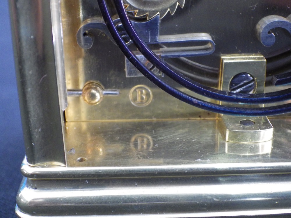 An antique brass carriage clock featuring an ornate silvered floral dial plate, Roman numerals, a top carrying handle, and an accompanying brass winding key. View IX
