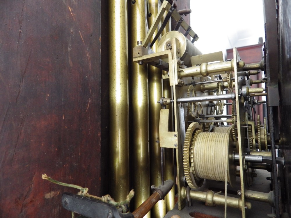 An antique flame mahogany longcase clock featuring a painted dial, swan-neck pediment with brass finials, and spirally turned column detailing. View X