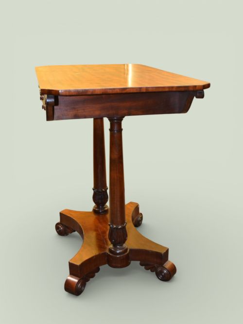 fig 1. A William IV mahogany side table featuring a rectangular top, frieze drawer with scroll carved brackets, twin column supports, and a shaped plinth base on scroll feet.