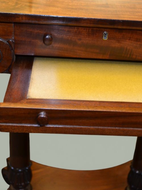fig 2. A William IV mahogany side table featuring a rectangular top, frieze drawer with scroll carved brackets, twin column supports, and a shaped plinth base on scroll feet.