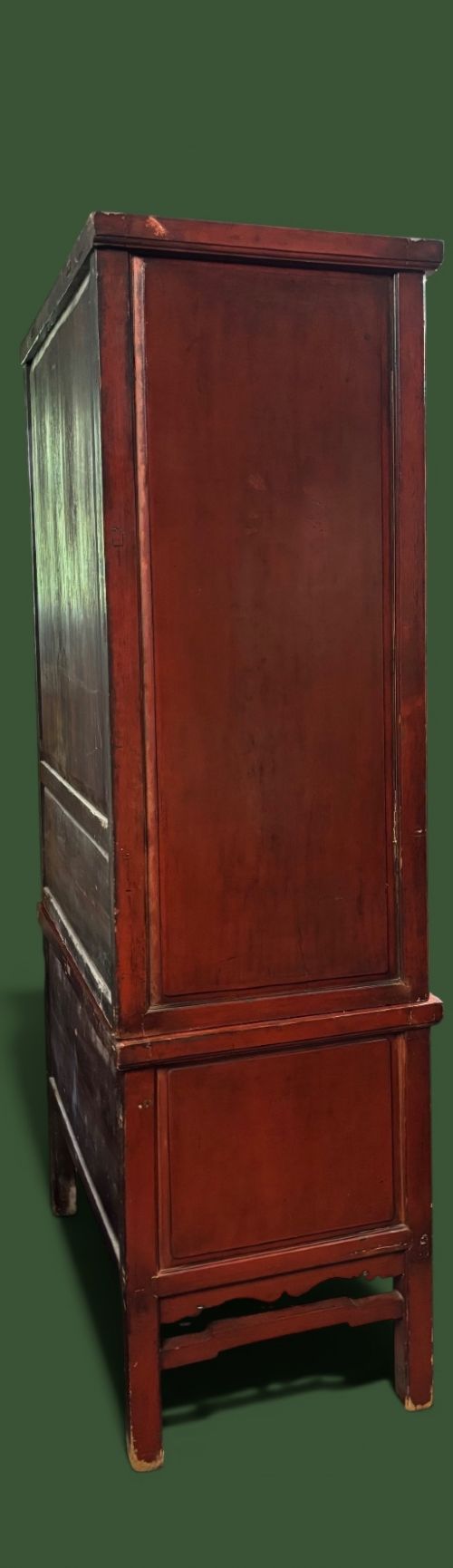 An antique Chinese tall wooden cabinet featuring red lacquered framing, gilded openwork wood carvings, black panels decorated with gold figures and floral motifs, and central brass hardware. View III