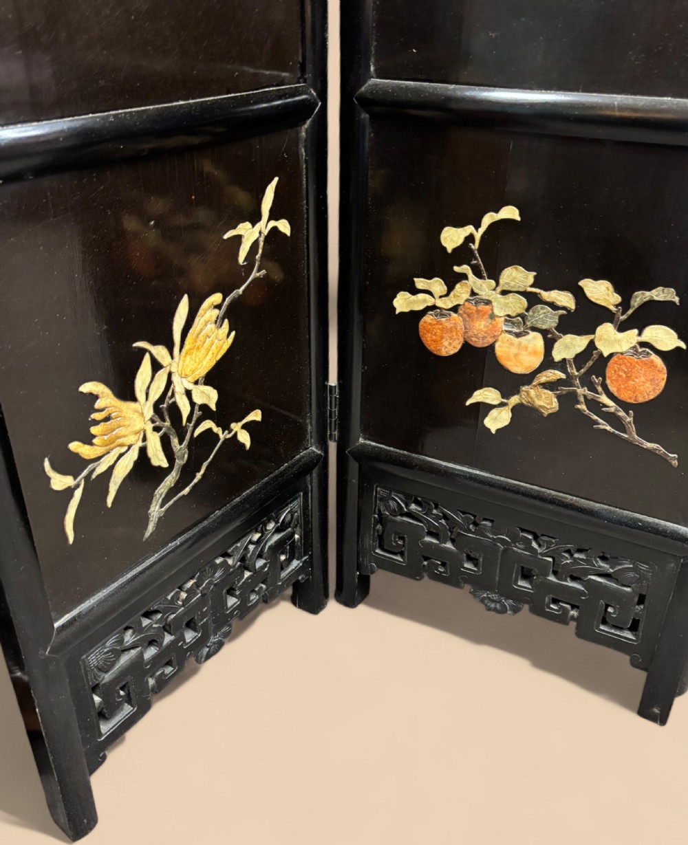 A six-panel black lacquered folding screen featuring raised stone inlays of birds and flowering branches with pierced fretwork lower panels. View V