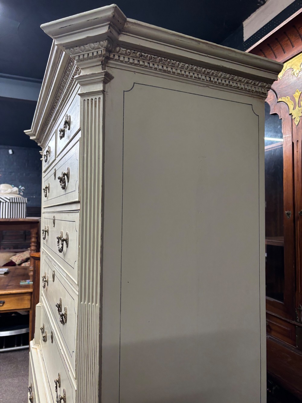 A tall cream-painted Georgian chest-on-chest featuring brass swan-neck handles, dentil moulding cornice, blue line detailing, and bracket feet. View IV