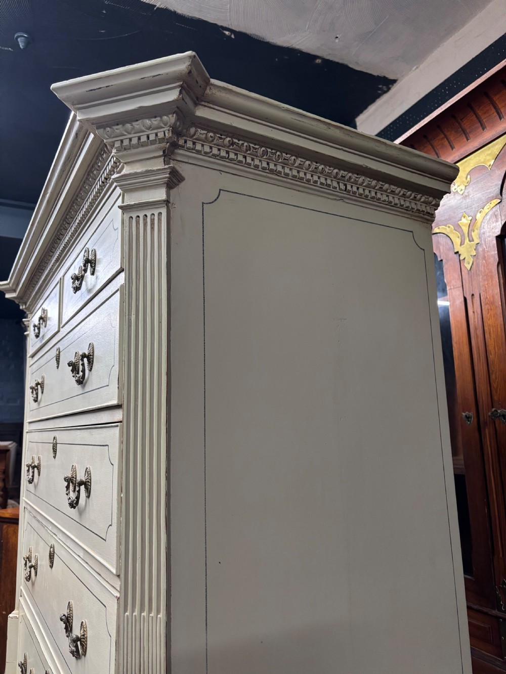 A tall cream-painted Georgian chest-on-chest featuring brass swan-neck handles, dentil moulding cornice, blue line detailing, and bracket feet. View VIII