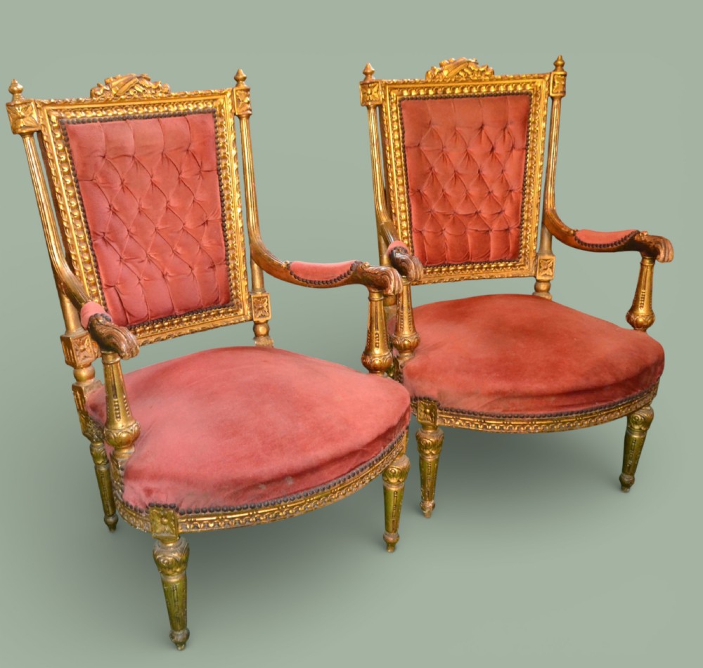 A pair of French giltwood armchairs featuring carved gold leaf frames, button-tufted red velvet backrests, padded armrests, and fluted turned legs. View II
