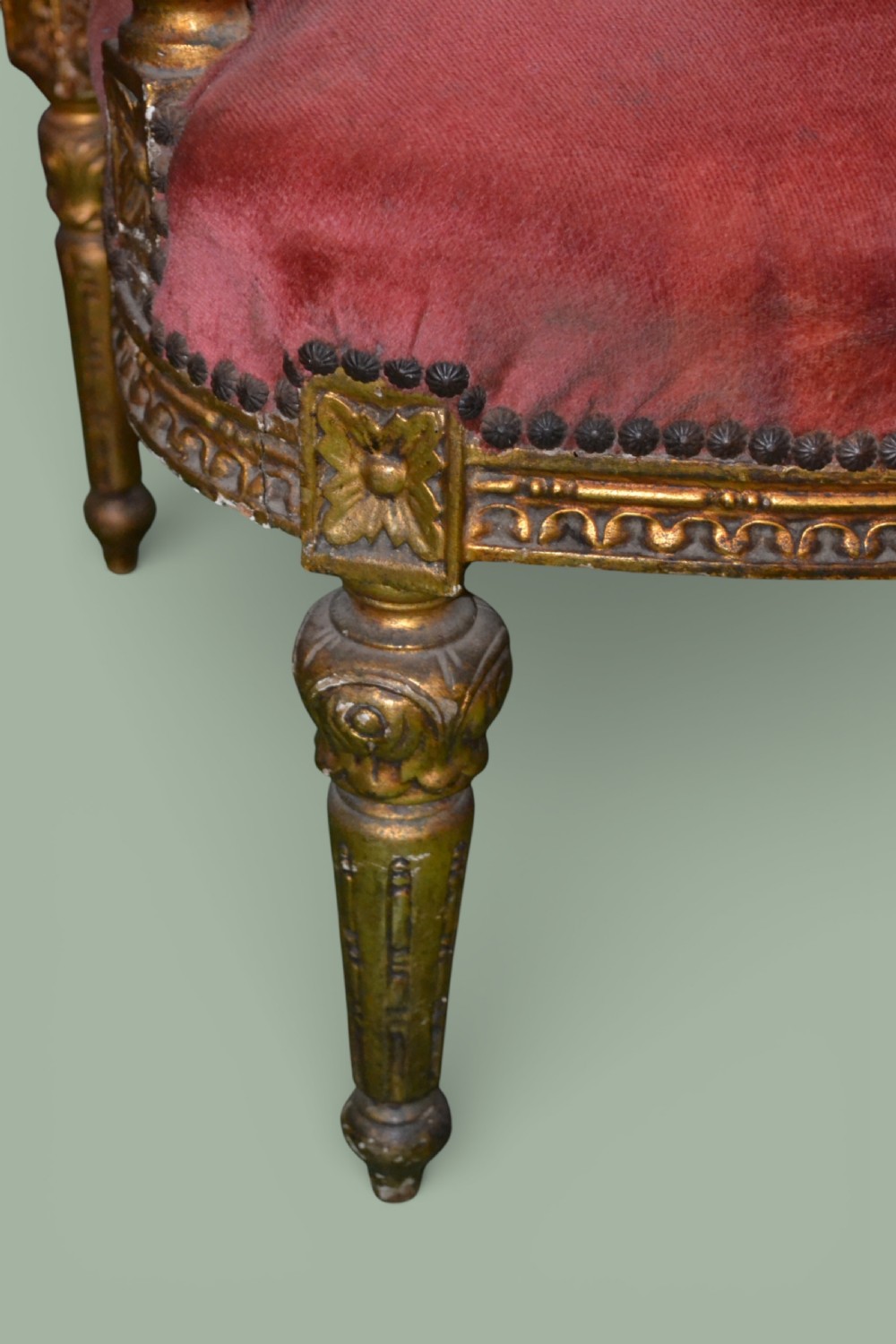 A pair of French giltwood armchairs featuring carved gold leaf frames, button-tufted red velvet backrests, padded armrests, and fluted turned legs. View V